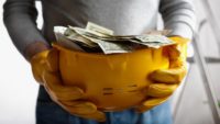 Person Holding Hard Hat With Money Getty Images