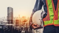 Construction Worker Holding Helmet Next to City