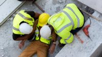 Two Construction Workers Helping Injured Worker