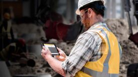 A subcontractor at a job site using an app on his tablet