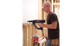 A drywall installer using a screwgun